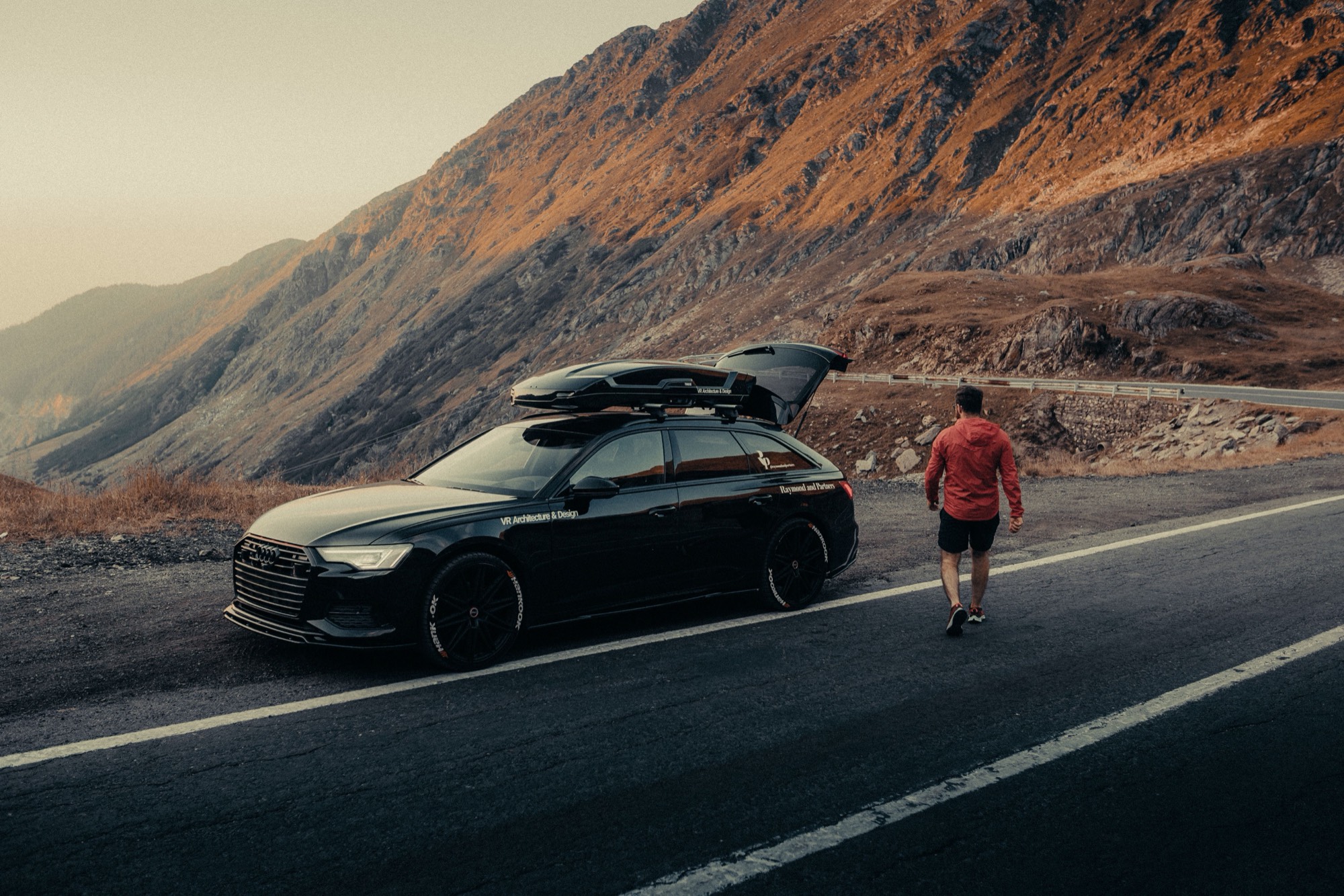 Car with a roof box on a mountain road at dusk